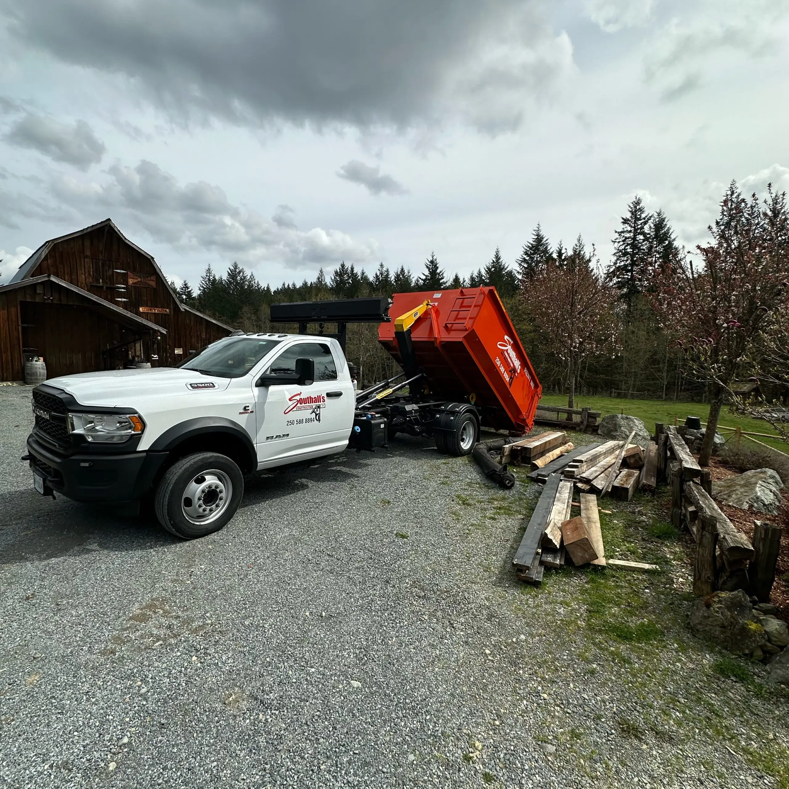 Southall Services dump truck delivering 12 yard bin rental near barn in Duncan BC