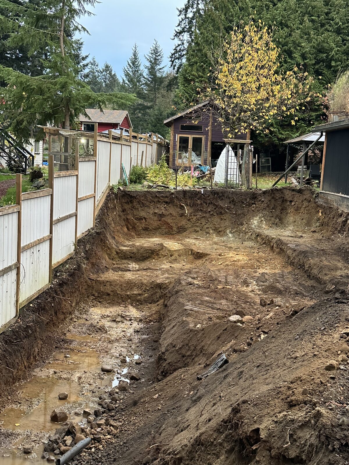 Foundation excavation and trench along the fence — garage addition and house underpinning project
