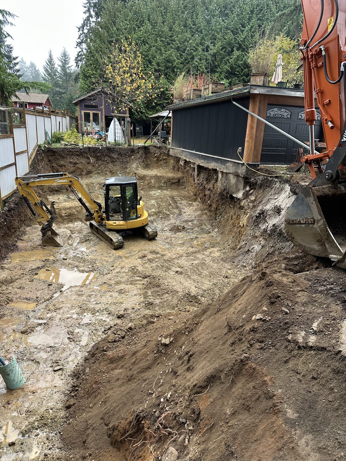 Excavators shaping the garage addition site — garage addition and house underpinning project