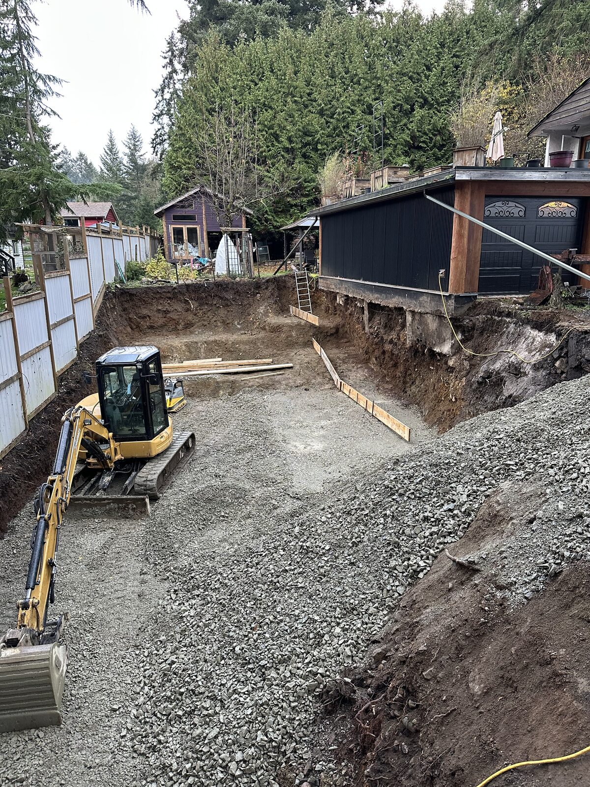 Gravel placement across the excavated foundation area — garage addition and house underpinning project