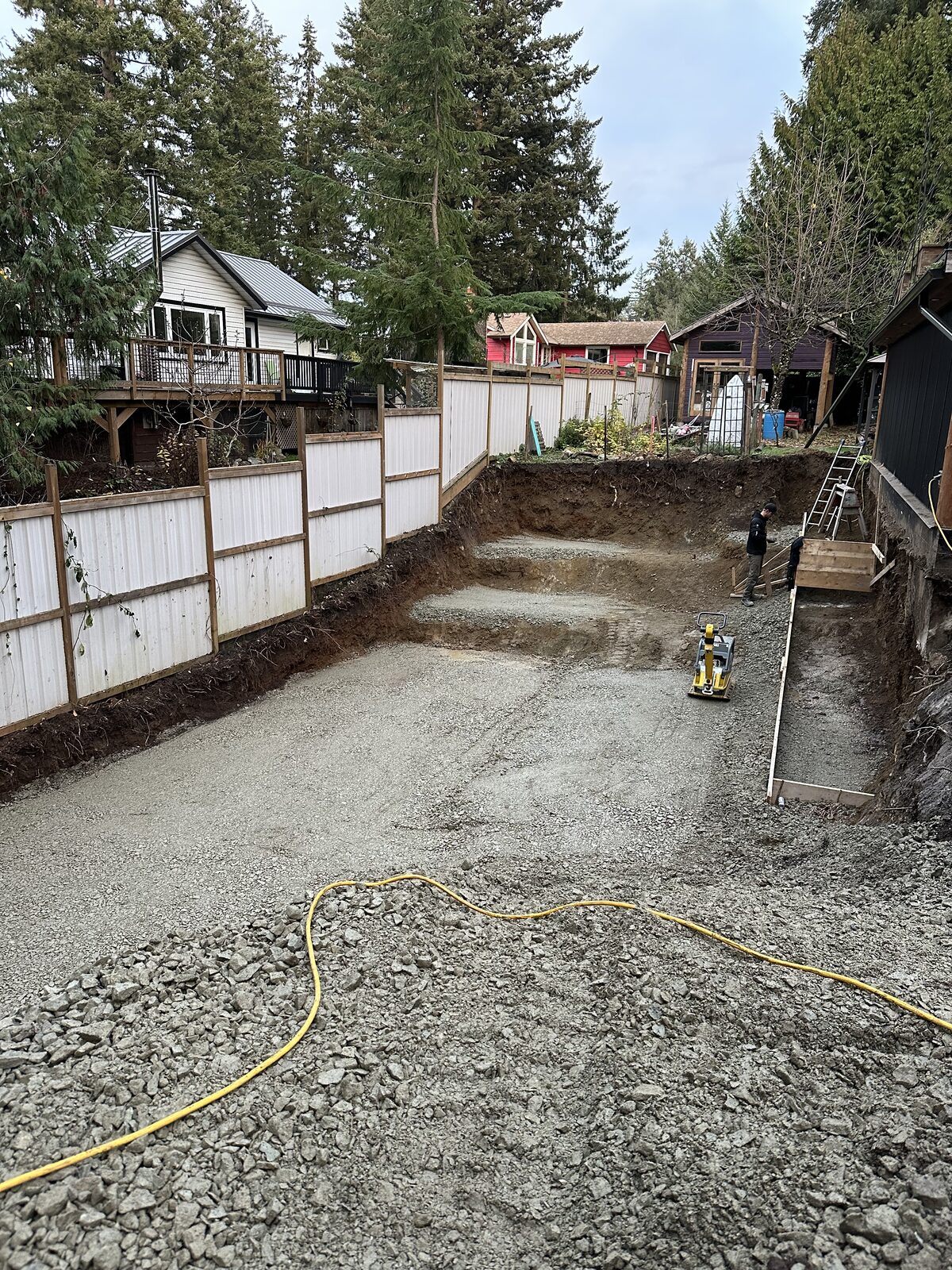 Gravel base prepared beside the existing house — garage addition and house underpinning project